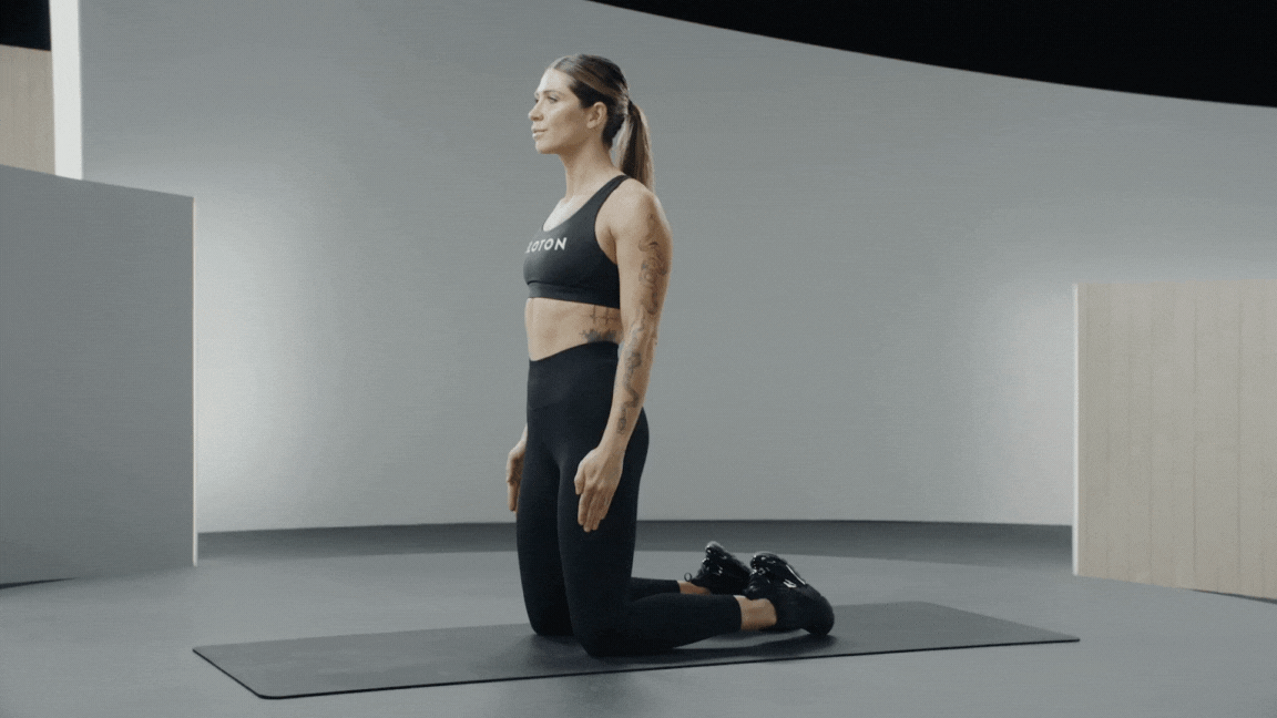 Peloton instructor Selena Samuela demonstrates a reverse Nordic curl or tall kneeling lean back quad exercuse.