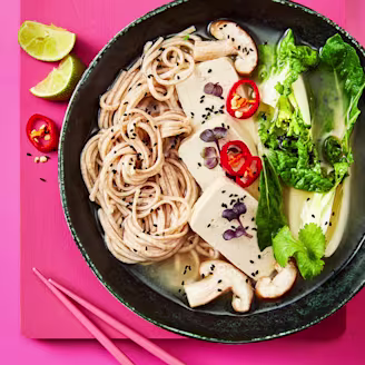 Miso soup made with Cauldron tofu served alongside Bok Choy in a dark bowl and lime on the side