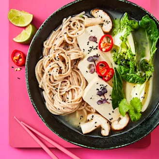 Miso soup made with Cauldron tofu served alongside Bok Choy in a dark bowl and lime on the side