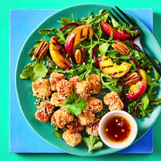 Cauldron breaded tofu bites with a hot maple sauce with a peach salad on a green bowl.