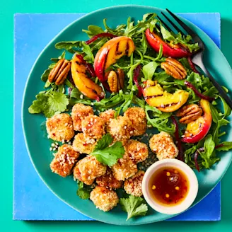 Cauldron breaded tofu bites with a hot maple sauce with a peach salad on a green bowl.