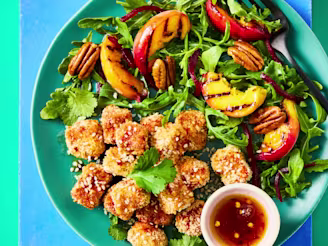 Cauldron breaded tofu bites with a hot maple sauce with a peach salad on a green bowl.