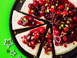 Cheesecake topped with cherries and cranberries on a black plate with a green background and stars.