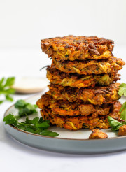 A stack of six tofu vegetable fritters served with coriander on the side 