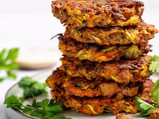 A stack of six tofu vegetable fritters served with coriander on the side