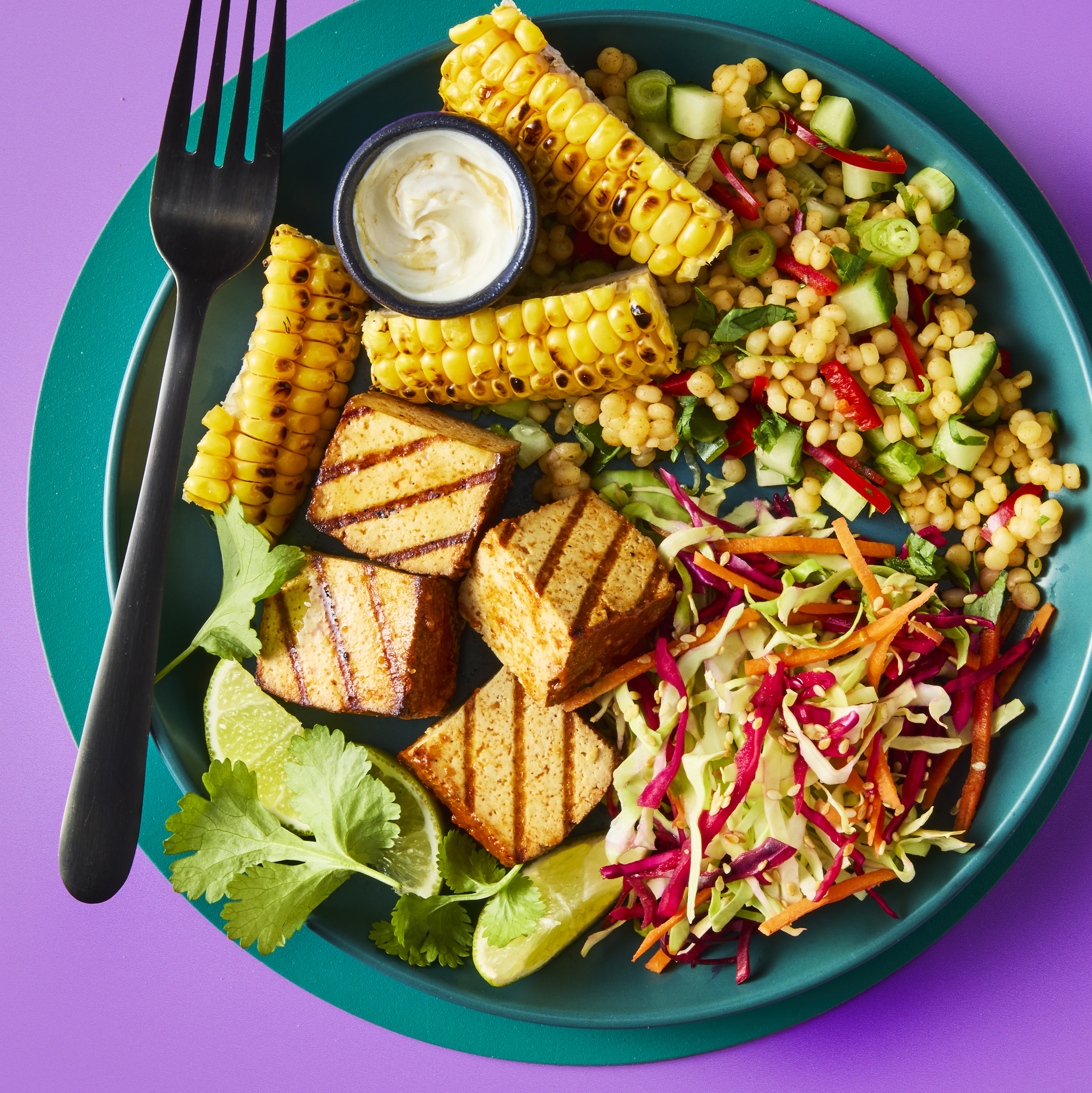 Smoky BBQ tofu poke bowl on a teal plate with couscous, slaw, and charred corn.