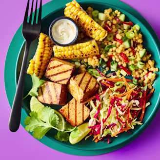 Smoky BBQ tofu poke bowl on a teal plate with couscous, slaw, and charred corn.