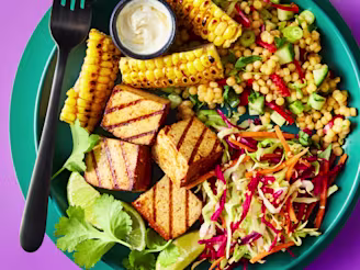Smoky BBQ tofu poke bowl on a teal plate with couscous, slaw, and charred corn.
