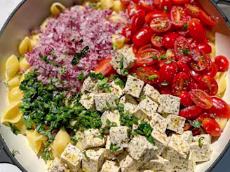 Tofu pasta salad with red onion and tomatoes served in a large dish