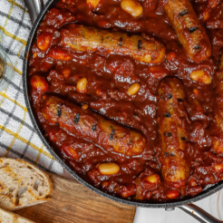 Boston Beans and Cauldron Sausage casserole served in a dark dish with bread on the side