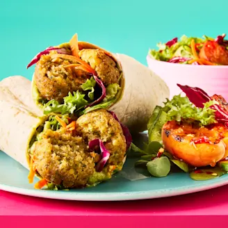 A stack of hot honey falafel and salad wraps on a light blue plate with a grilled apricot side salad.