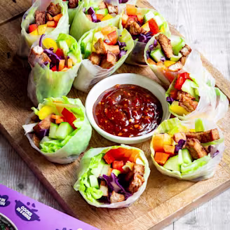 Tofu rolls wrapped in rice paper with colourful vegetables and dipping sauce.