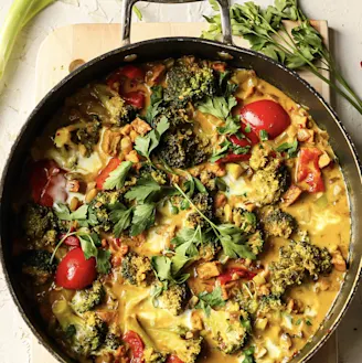 Coconut and Tofu curry with broccoli and tomatoes served in a dark dish