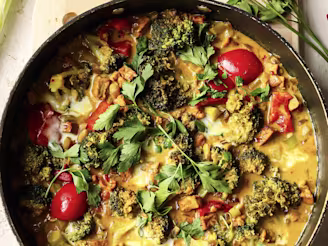 Coconut and Tofu curry with broccoli and tomatoes served in a dark dish