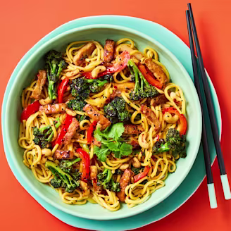 Cauldron Marinated Tofu Pieces with noodles, chopped vegetables and broccoli in a blue bowl with black chopsticks.