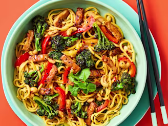Cauldron Marinated Tofu Pieces with noodles, chopped vegetables and broccoli in a blue bowl with black chopsticks.