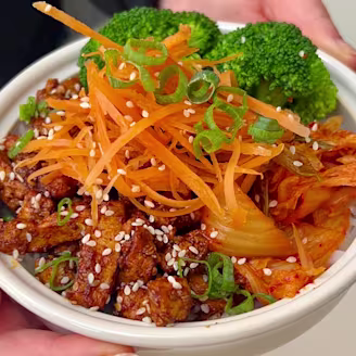 Cauldron marinated tofu pieces with onion, broccoli, carrots and rice in a soy sauce.