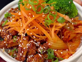 Cauldron marinated tofu pieces with onion, broccoli, carrots and rice in a soy sauce.