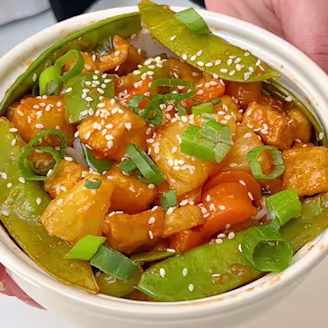 A Sweet & Sour Stir-Fry with Cauldron tofu pieces, pineapple, peppers, snap peas and rice in a soy sauce. 