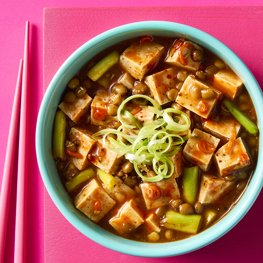 Vegan Mafo Tofu with chilli, peppercorns, lentils and onion in a blue bowl on pink background.