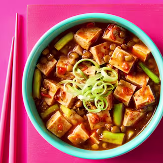 Vegan Mafo Tofu with chilli, peppercorns, lentils and onion in a blue bowl on pink background.