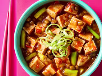 Vegan Mafo Tofu with chilli, peppercorns, lentils and onion in a blue bowl on pink background.