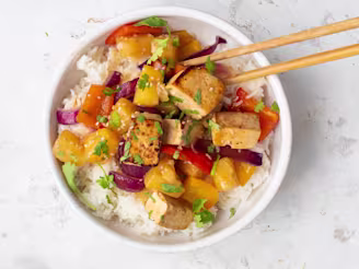 Sweet and sour tofu in bowl with white rice and chopsticks.