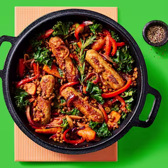Cauldron Lincolnshire Sausage and lentil casserole with roasted veg served in a dark dish with a green background 