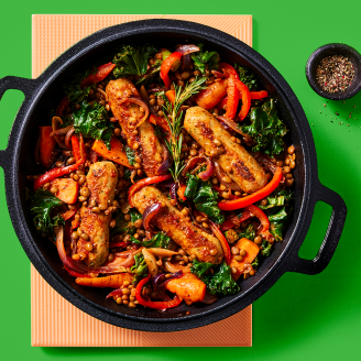 Cauldron Lincolnshire Sausage and lentil casserole with roasted veg served in a dark dish with a green background 