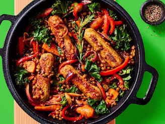 Cauldron Lincolnshire Sausage and lentil casserole with roasted veg served in a dark dish with a green background
