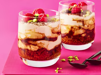 Two tiramisu in glass cups with a pink background