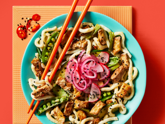 Vegan satay stir fry with udon noodles showcasing Cauldron Tofu and a vegetable served on a blue bowl with orange chopsticks 