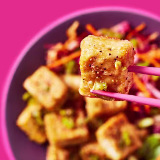 Cauldron Extra Firm Tofu being picked up with chopsticks with a bowl in the background