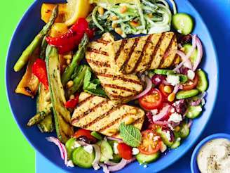 Greek Tofu Bowl served on a plate with grilled tofu, Greek salad, chargrilled vegetables, and tzatziki on the side.