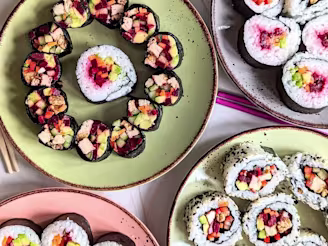 Four plates of vegan sushi rolls with Cauldron marinated tofu pieces filled with seaweed, carrot, cucumber, avocado, pepper, beetroot and sesame seeds.