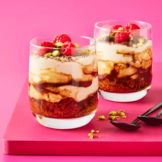 Two tiramisu in glass cups with a pink background 