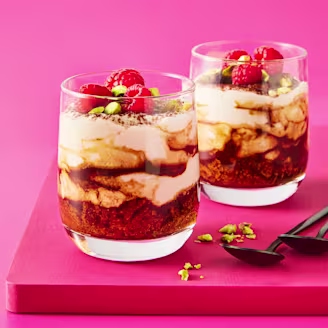 Two tiramisu in glass cups with a pink background