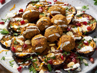 Aubergine and falafel bake loaded with tahini, pomegranate & flaked almonds on a plate
