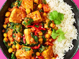 Tofu, Spinach & Chickpea Curry with white rice served on a black plate.
