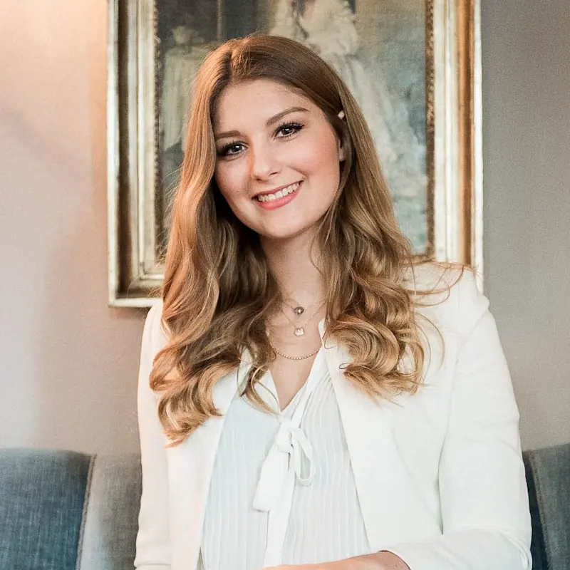 Georgia Näder sitting on a sofa and smiling into the camera.