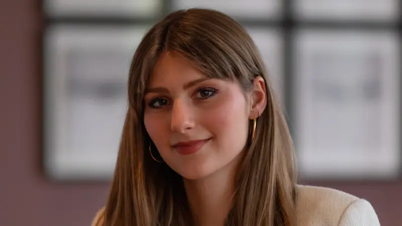 Georgia Näder sitzt auf einem Sofa und lächelt in die Kamera.