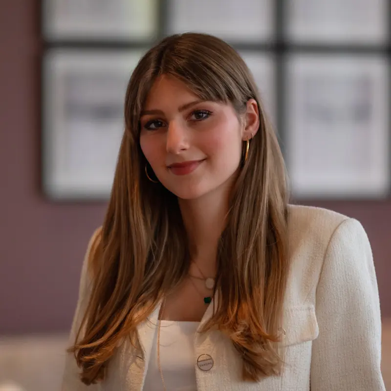 Georgia Näder sitting on a sofa and smiling into the camera.