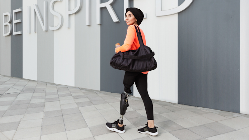 Ottobock brand ambassador Zainab Al-Eqabi with a sports bag in front of a large “Be Inspired” lettering. She is wearing her Ottobock Genium X3 prosthesis.