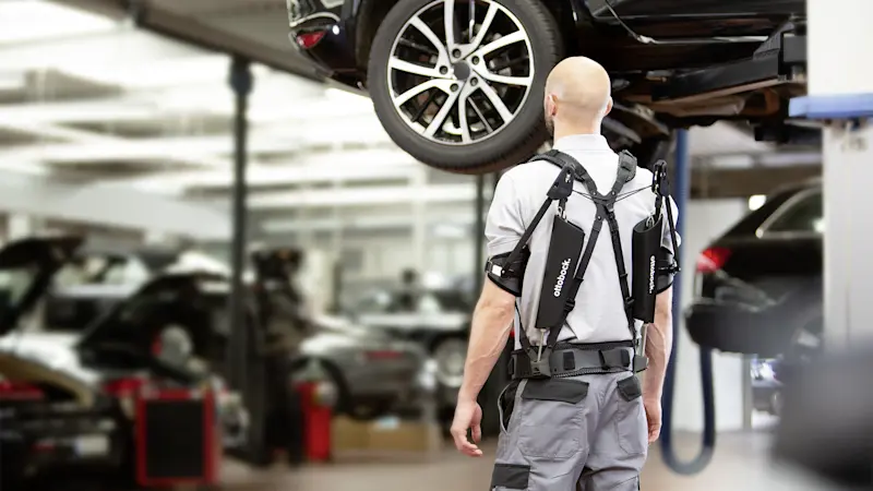 Anwender des Ottobock Paexo Exoskelett arbeitet in der Autowerkstatt.