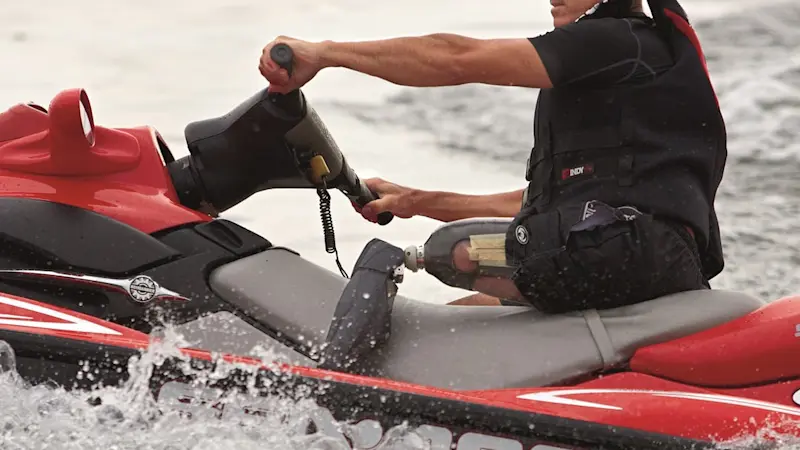 Mann mit einer Beinprothese Genium X3 fährt auf einem rot-grauen Jetski im Wasser.