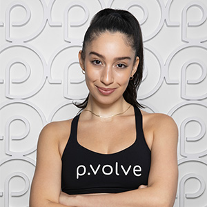 Woman wearing a 'p.volve' tank top, smiling in front of a logo background.