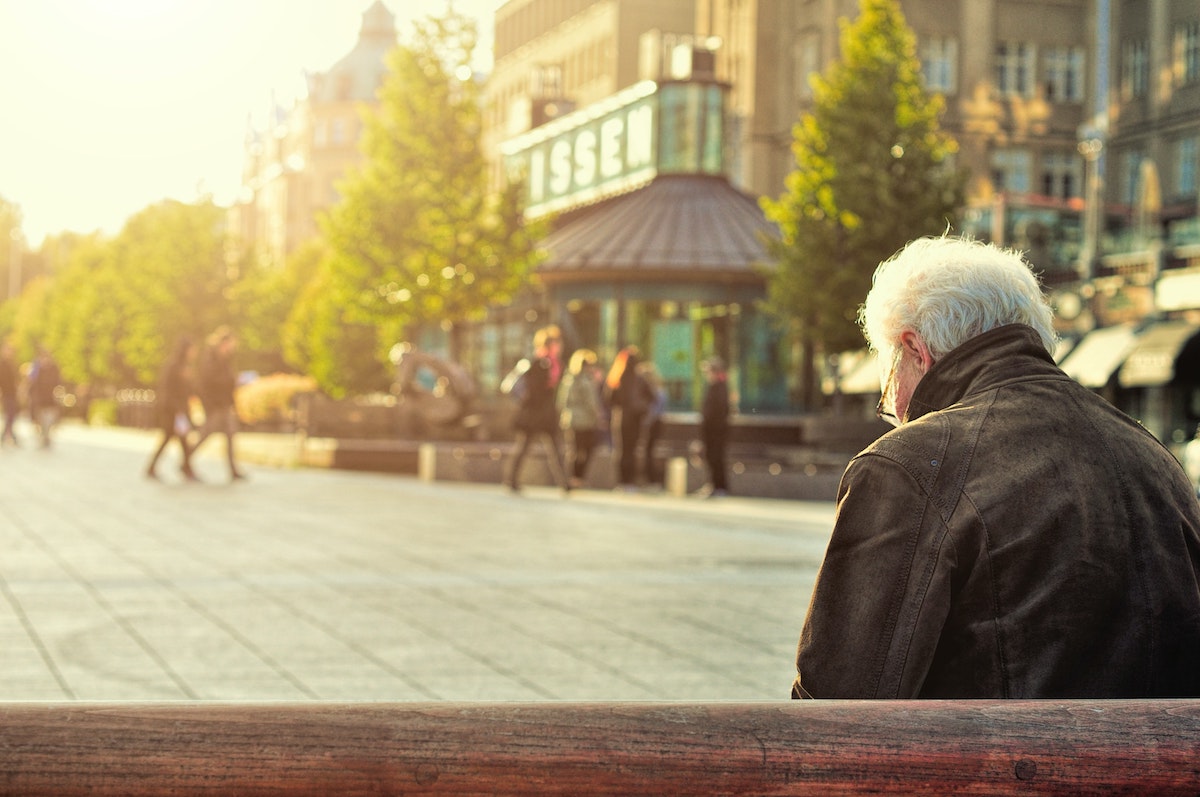 man sits outside in a crowded plaza