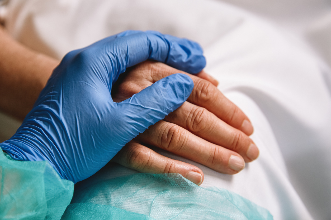hand in a surgical glove holds the hand of a patient
