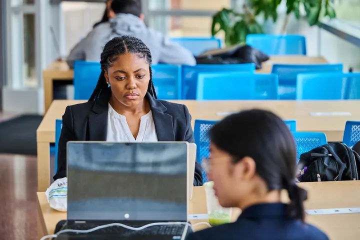 Student in professional attire works from a laptop