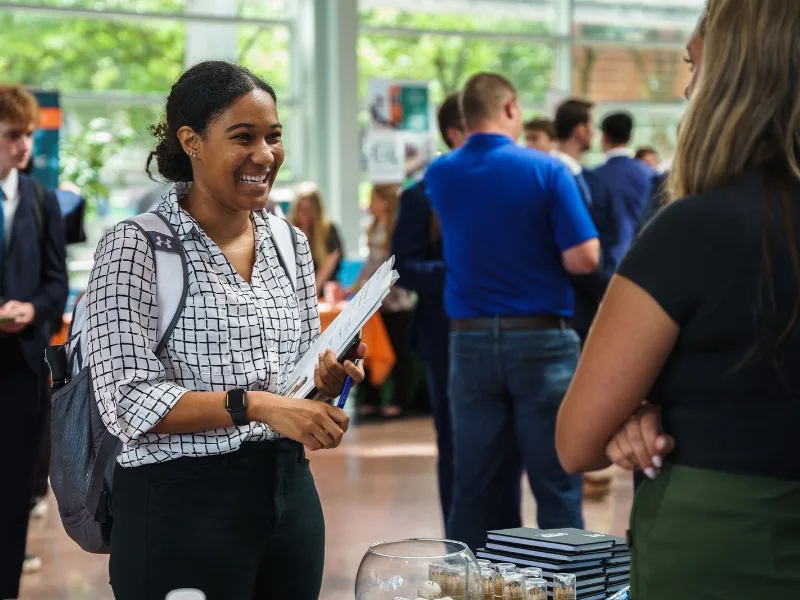 Student smiles at a vendor at a career fair